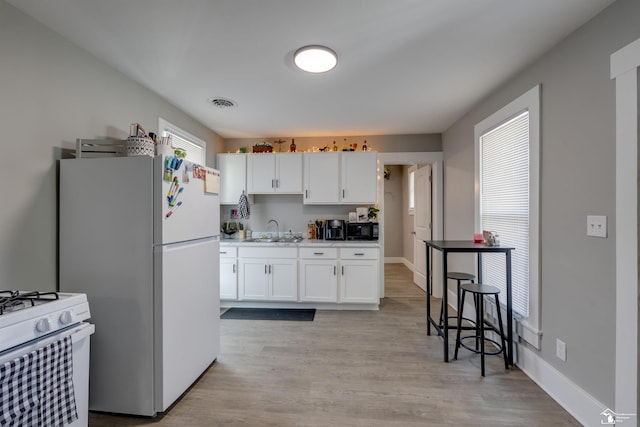 kitchen with white cabinetry, sink, white appliances, and light wood-type flooring