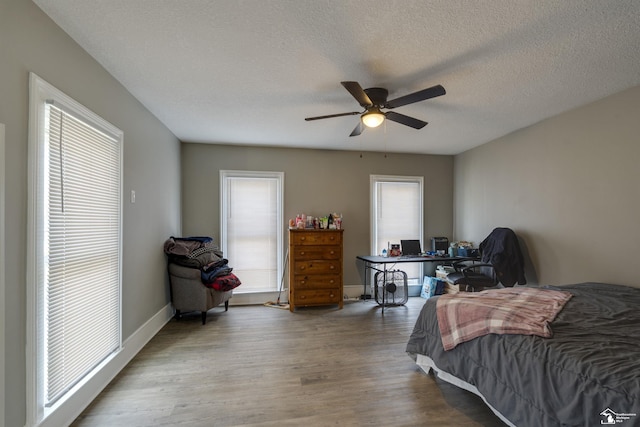 bedroom featuring multiple windows, hardwood / wood-style flooring, and a textured ceiling