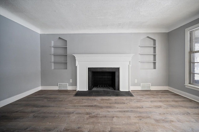 unfurnished living room with dark wood-type flooring, built in shelves, and a textured ceiling