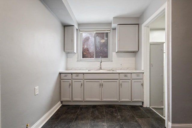 kitchen with tasteful backsplash, gray cabinets, and sink