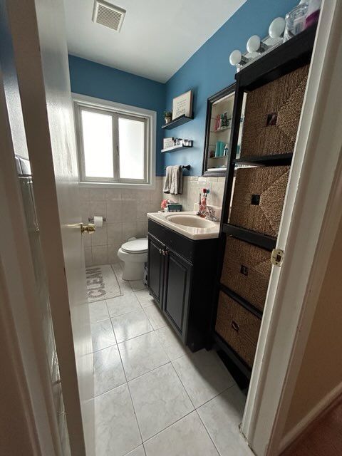 bathroom featuring vanity, tile walls, tile patterned floors, and toilet