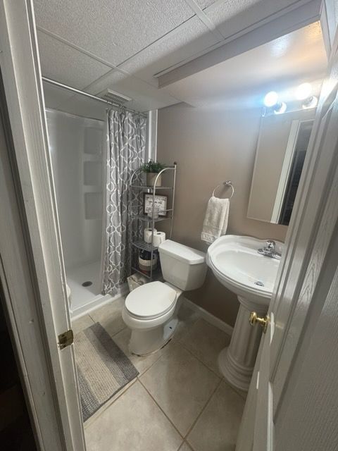 bathroom featuring a shower with curtain, sink, tile patterned floors, and toilet