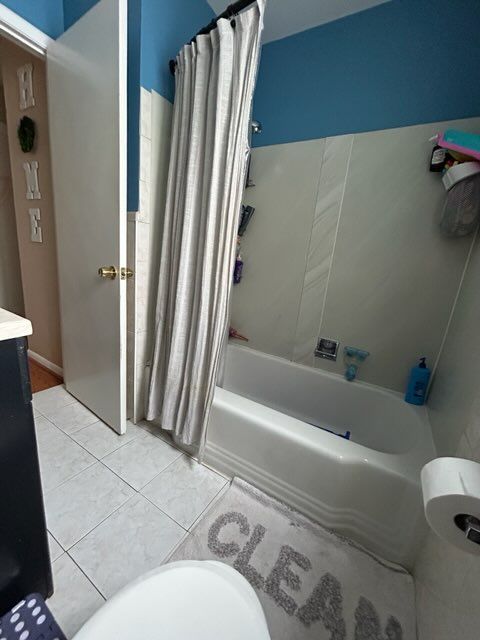 full bathroom featuring vanity, tile patterned floors, toilet, and shower / bath combo with shower curtain