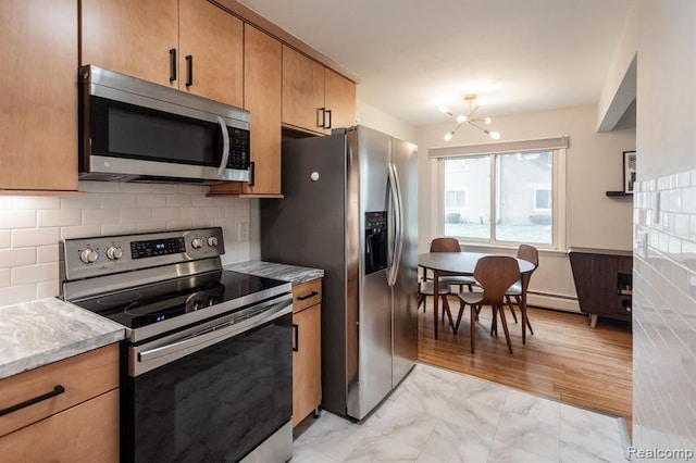 kitchen featuring tasteful backsplash, a baseboard heating unit, stainless steel appliances, and a chandelier