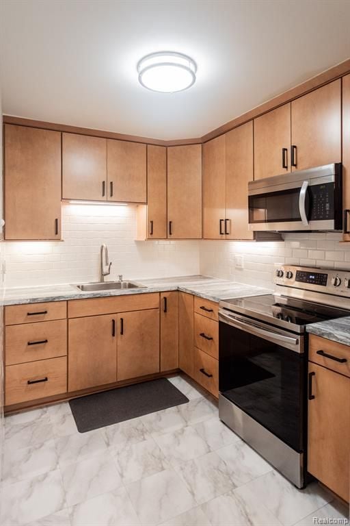 kitchen with sink, decorative backsplash, light brown cabinets, and appliances with stainless steel finishes