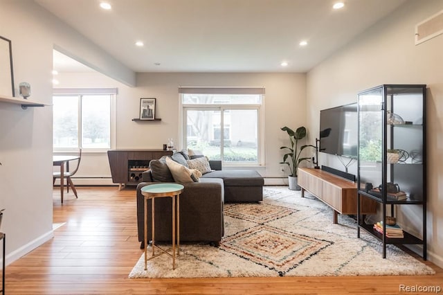 living room featuring a baseboard heating unit and light wood-type flooring