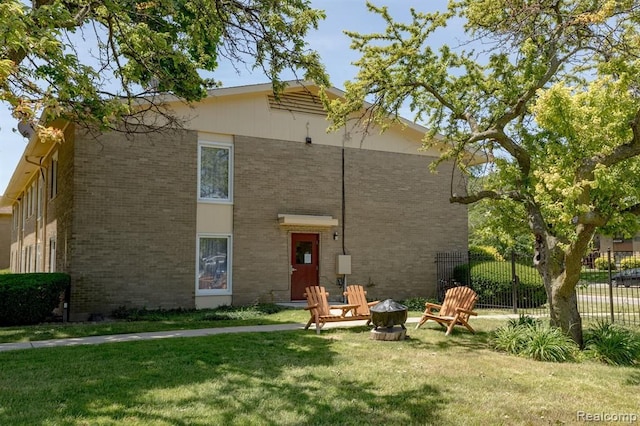 back of house with an outdoor fire pit and a yard