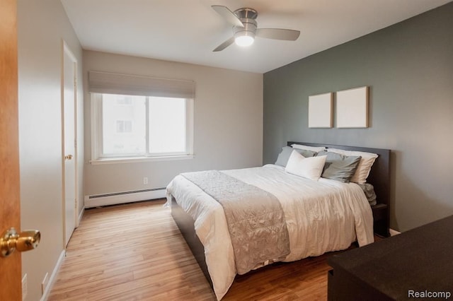 bedroom featuring a baseboard heating unit, light hardwood / wood-style flooring, and ceiling fan