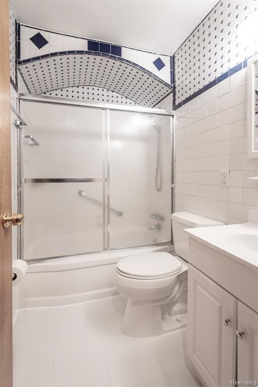 full bathroom with toilet, combined bath / shower with glass door, tile walls, vanity, and tile patterned flooring