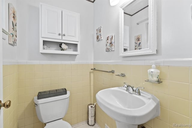 bathroom featuring sink, tile walls, and toilet