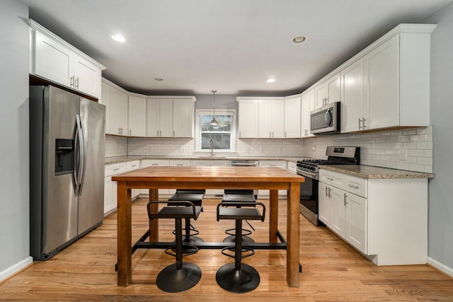 kitchen featuring hanging light fixtures, white cabinetry, appliances with stainless steel finishes, and sink