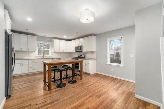 kitchen with sink, appliances with stainless steel finishes, white cabinetry, tasteful backsplash, and light stone countertops