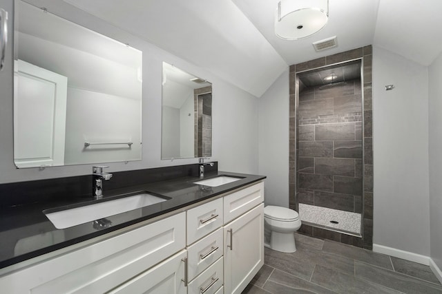 bathroom featuring lofted ceiling, toilet, vanity, and a tile shower