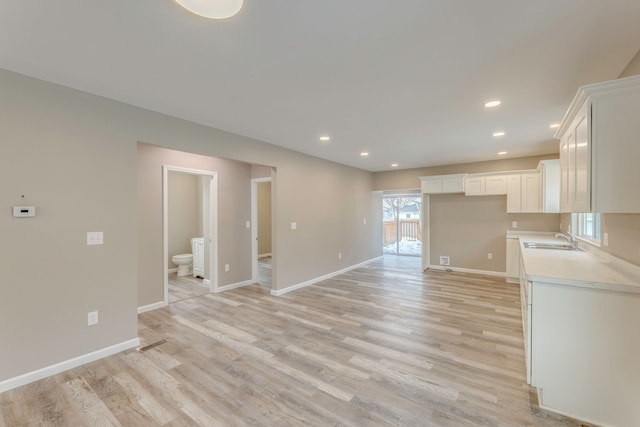 unfurnished living room featuring sink and light hardwood / wood-style floors