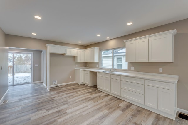 kitchen featuring sink, light hardwood / wood-style flooring, and white cabinets