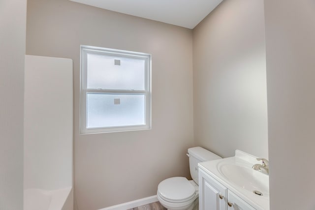 bathroom featuring hardwood / wood-style flooring, a tub to relax in, vanity, and toilet