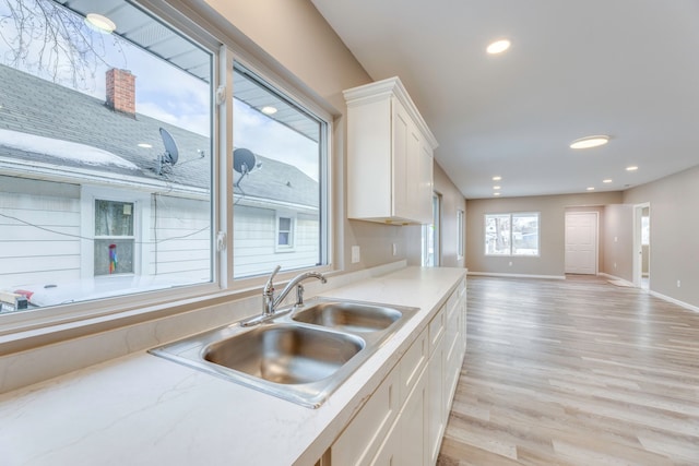 kitchen with light hardwood / wood-style floors, sink, and white cabinets