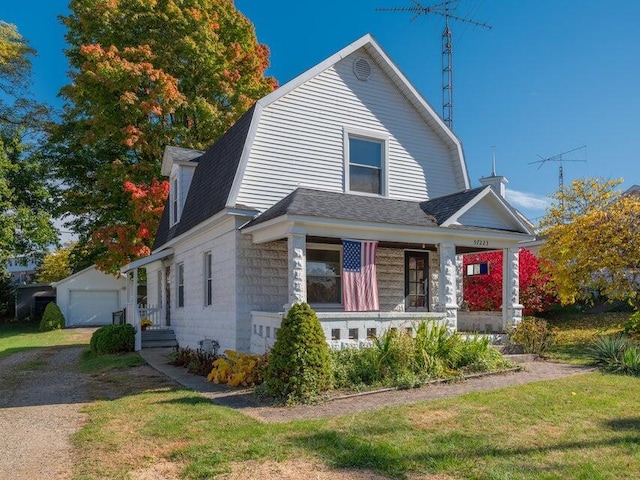 view of front of house featuring an outbuilding, a porch, a garage, and a front yard