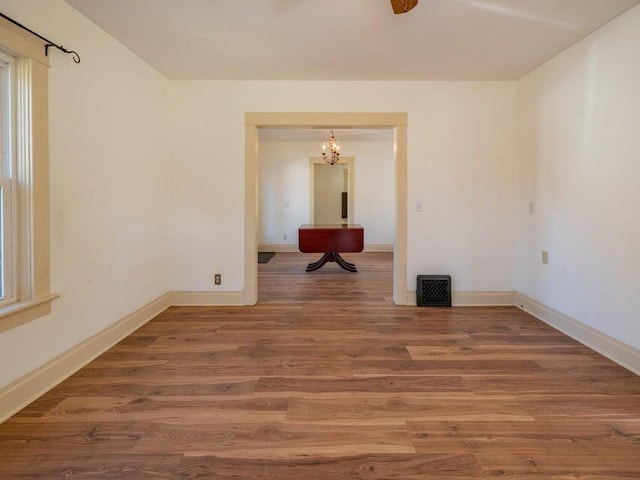 unfurnished room featuring an inviting chandelier and wood-type flooring