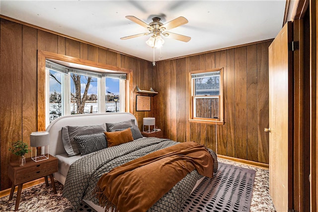 bedroom featuring ceiling fan and wooden walls