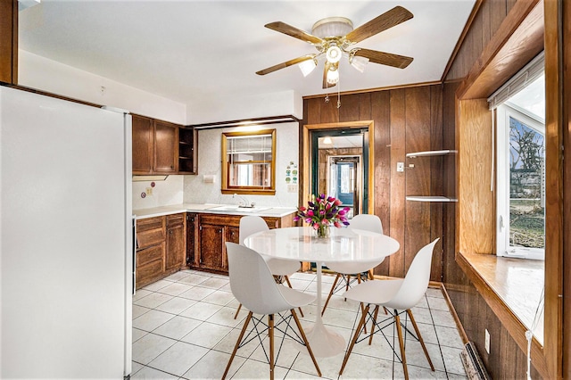 kitchen featuring ceiling fan, wooden walls, sink, and light tile patterned floors