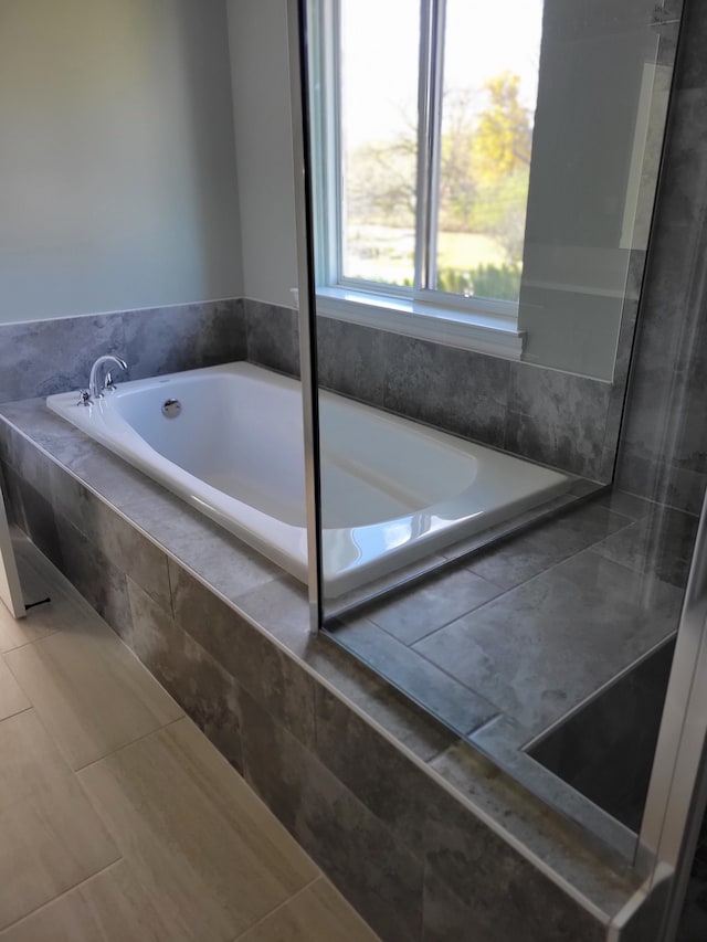 bathroom with tile patterned flooring and a relaxing tiled tub