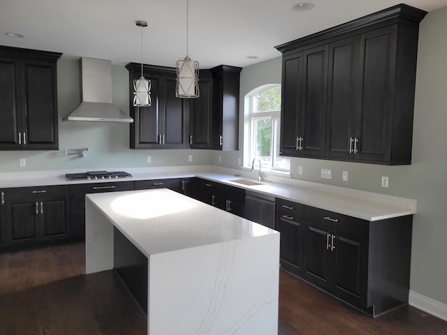 kitchen featuring appliances with stainless steel finishes, a kitchen island, pendant lighting, sink, and wall chimney exhaust hood