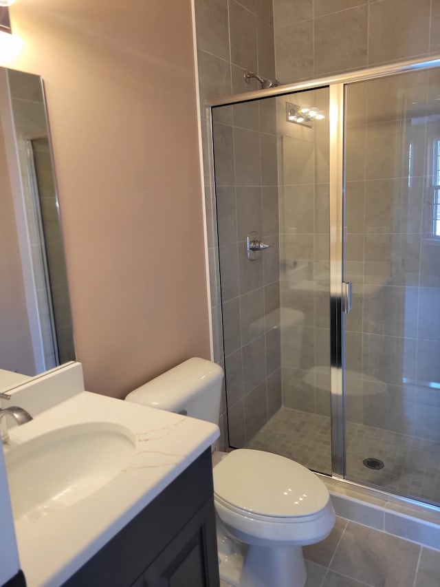 bathroom with vanity, tile patterned flooring, a shower with shower door, and toilet