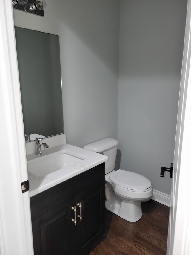 bathroom with wood-type flooring, toilet, and vanity