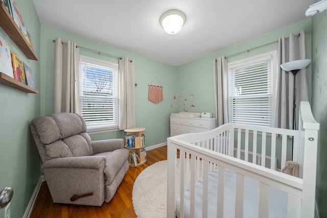 bedroom featuring hardwood / wood-style flooring and a crib