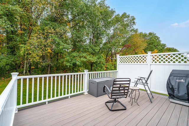 wooden deck featuring a grill and a yard