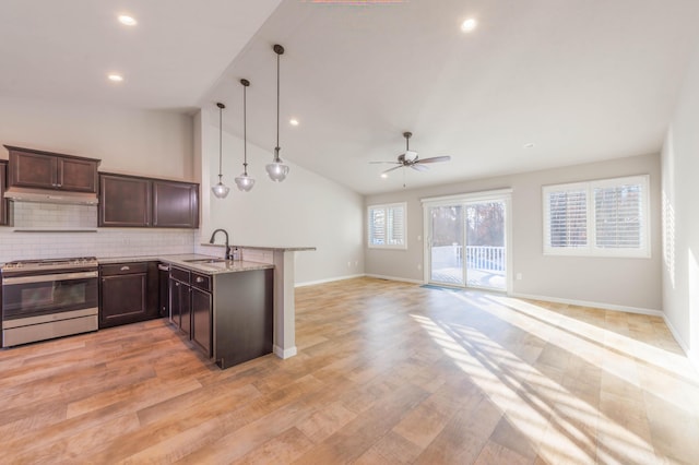 kitchen featuring sink, hanging light fixtures, stainless steel range, kitchen peninsula, and light stone countertops