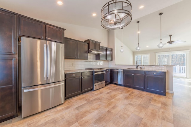 kitchen featuring stainless steel appliances, decorative light fixtures, kitchen peninsula, and sink