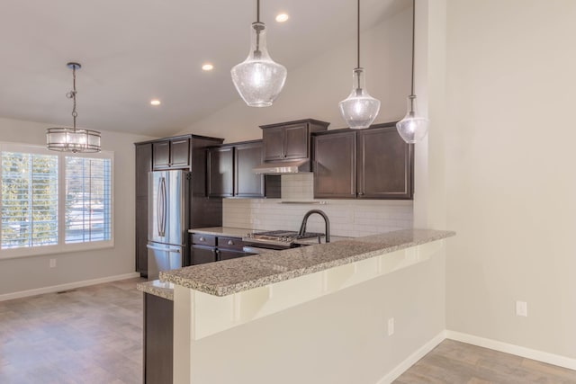 kitchen featuring hanging light fixtures, backsplash, stainless steel appliances, dark brown cabinetry, and kitchen peninsula