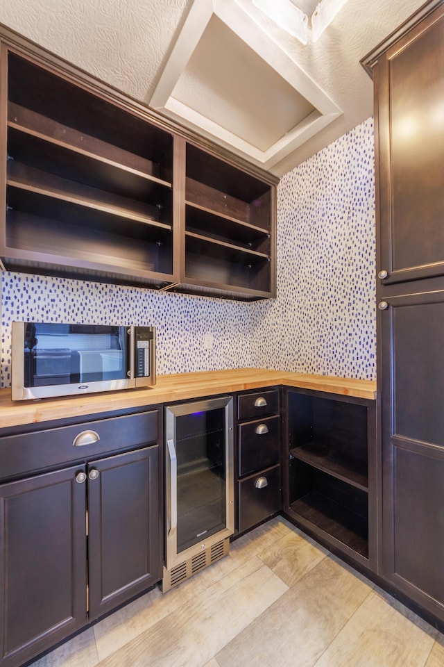 kitchen with dark brown cabinets, beverage cooler, and butcher block countertops