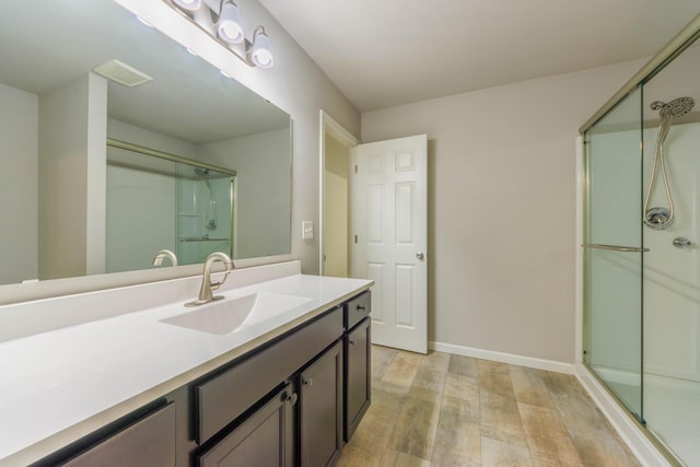 bathroom with a shower with door, wood-type flooring, and vanity