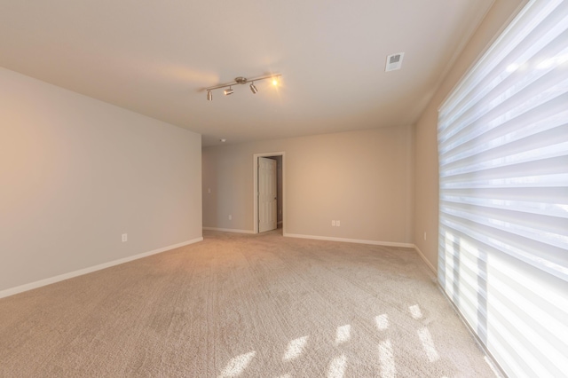 carpeted spare room with track lighting