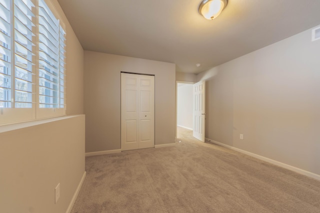 unfurnished bedroom with light carpet and a closet