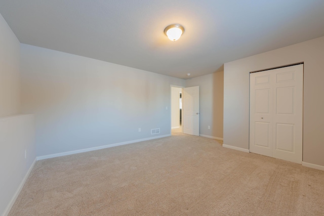 unfurnished bedroom with a closet and light carpet