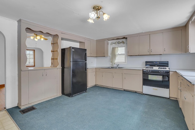 kitchen featuring black fridge, white gas range, sink, and a wealth of natural light