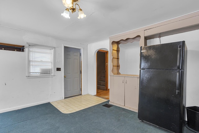 kitchen with black fridge, carpet floors, and a notable chandelier