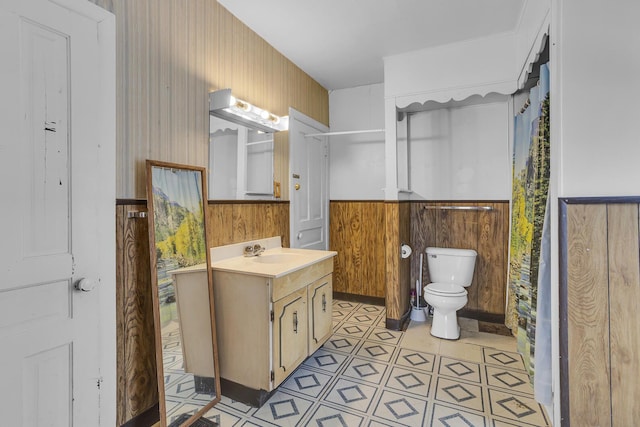 bathroom with a shower with curtain, wooden walls, vanity, and toilet