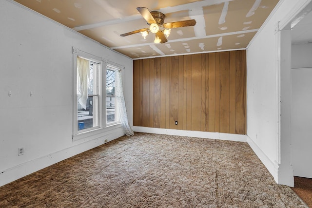 carpeted empty room with wooden walls and ceiling fan