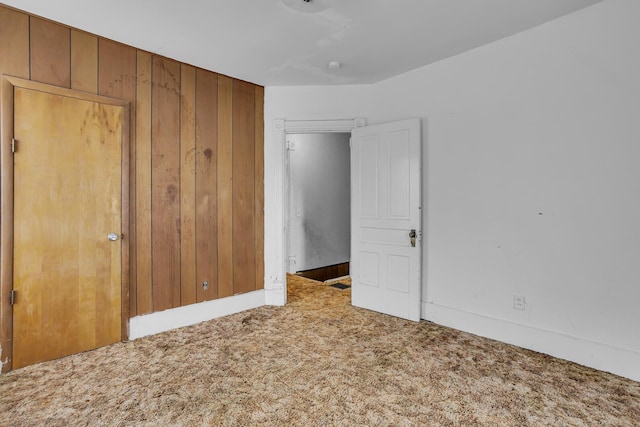 unfurnished bedroom with wooden walls and carpet flooring