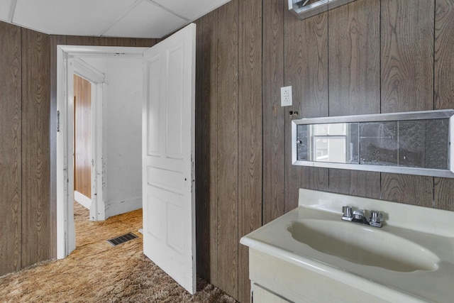 bathroom featuring vanity, wooden walls, and a drop ceiling