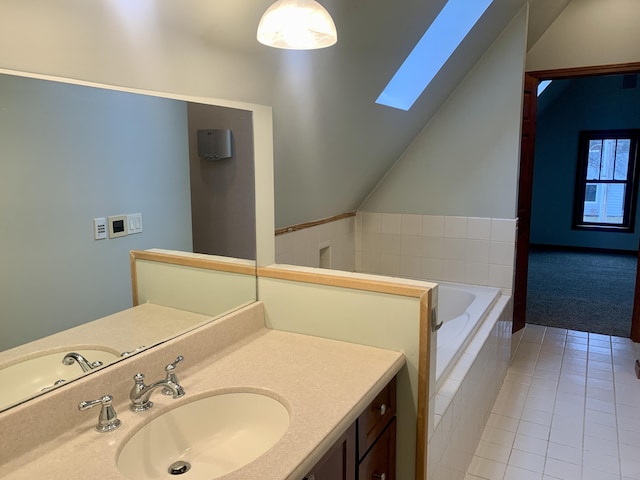 bathroom with vanity, lofted ceiling with skylight, tile patterned flooring, and tiled bath