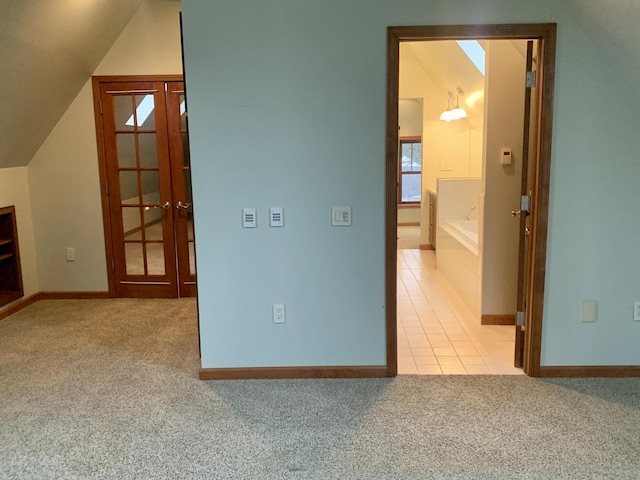 interior space featuring vaulted ceiling, light colored carpet, and french doors