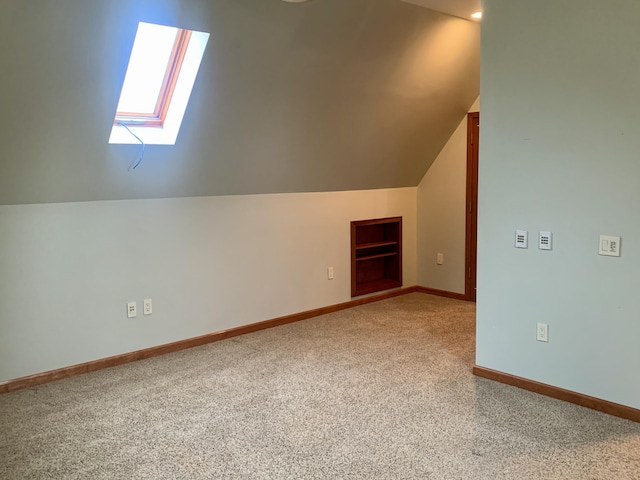 additional living space featuring built in shelves, carpet flooring, and lofted ceiling with skylight