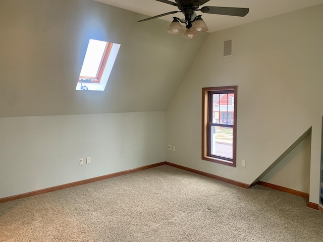 additional living space with ceiling fan, carpet flooring, and lofted ceiling with skylight