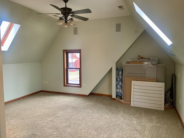 additional living space featuring ceiling fan, vaulted ceiling with skylight, and carpet flooring